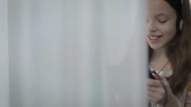 Güzel küçük kız kulaklıklarla tablet ve gülmek komik video izleme.