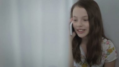 Güzel mutlu küçük kız smartphone üzerinde konuşurken duygusal