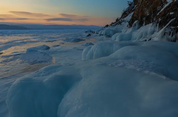 Hatalmas jégcsapok napkeltekor sziklák közelében. — Stock Fotó