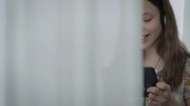 Güzel küçük kız kulaklıklarla tablet ve gülmek komik video izleme.