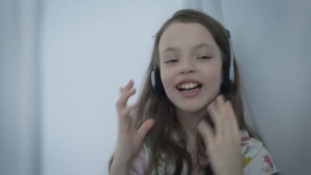 Hermosa niña en auriculares cantando canción emocionalmente y bailando — Vídeos de Stock