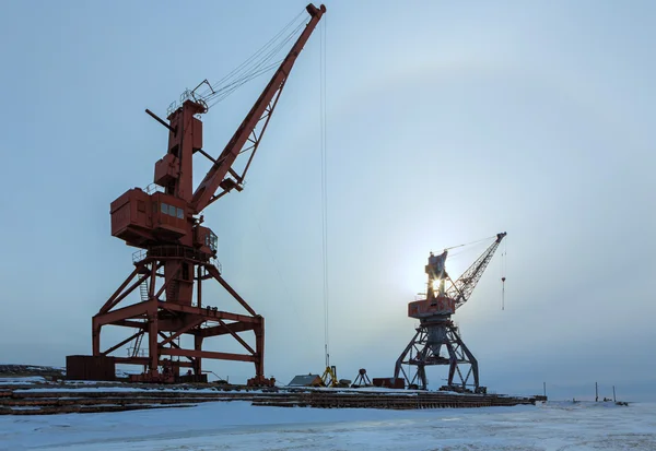 Schepen vracht kranen op de oever van het Baikalmeer in de winter bij zonsondergang. — Stockfoto