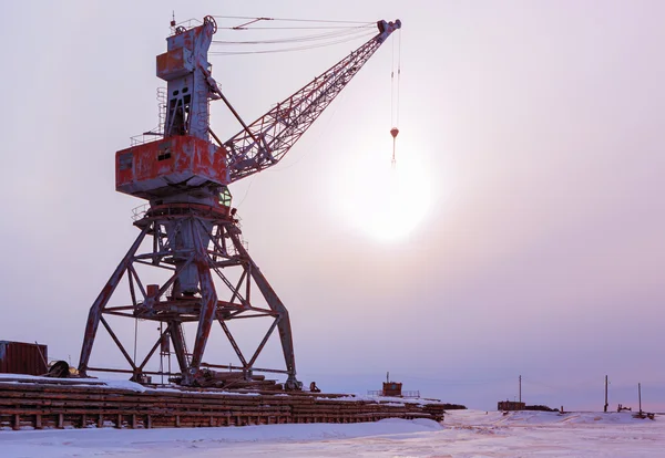 Ships cargo cranes on shore of Lake Baikal in winter at sunset. Royalty Free Stock Images