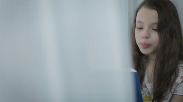 Hermosa niña leyendo un interesante libro por ventana . — Vídeos de Stock