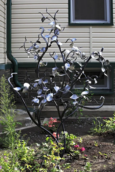 Bel arbre en fer forgé sur la pelouse près de la maison . — Photo