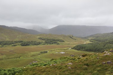 Bulutlar dağlar ve yeşil vadi üzerinde yalan.