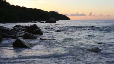 Dalgalar Anse Lazio plaj gün batımında.