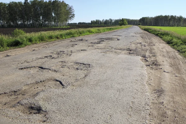 破碎的织物的鄂木斯克地区的农村道路. — 图库照片