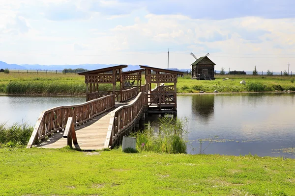 Puente de amor y un viejo molino. Complejo Turístico Siberiano Podvorye . —  Fotos de Stock