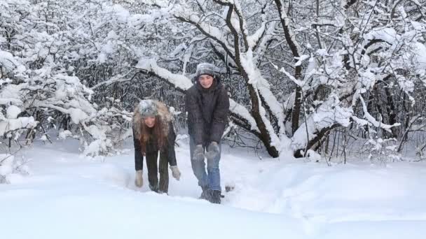 Glada vackra pojke och flicka har roligt duschat med snö i vinter park. — Stockvideo