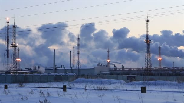 在落日的天空背景的炼油厂。雪人下雪的冬天的晚上. — 图库视频影像