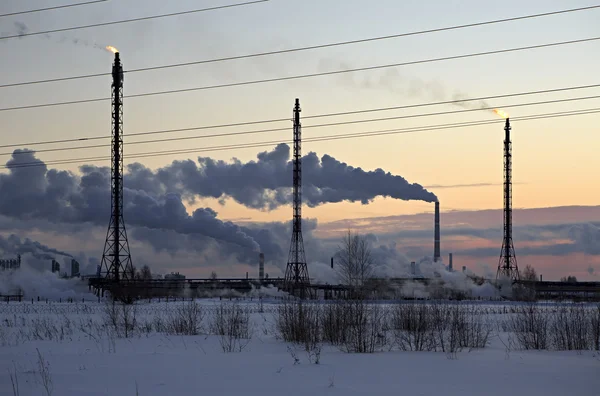 Refinería al atardecer fondo cielo. Tarde de invierno nevada helada . —  Fotos de Stock