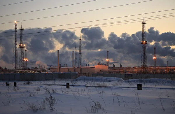 Raffinerie bei Sonnenuntergang Himmel Hintergrund. frostig schneebedeckter Winterabend. — Stockfoto