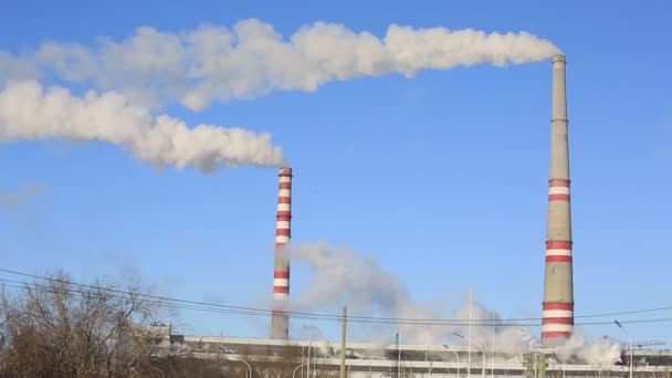 Termik santral güneşli soğuk günde. Endüstriyel duman boruları mavi gökyüzü karşı. — Stok video