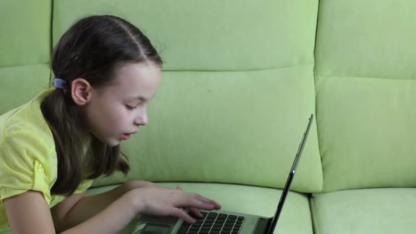 Schönes kleines Mädchen spricht und tippt auf Laptop. — Stockvideo