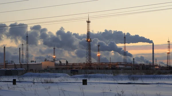 Refinería al atardecer fondo cielo. Tarde de invierno nevada helada . — Foto de Stock