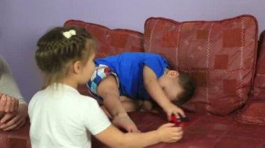 Küçük çocuk makine kanepenin üstüne alır. Mutlu aile oynarken.