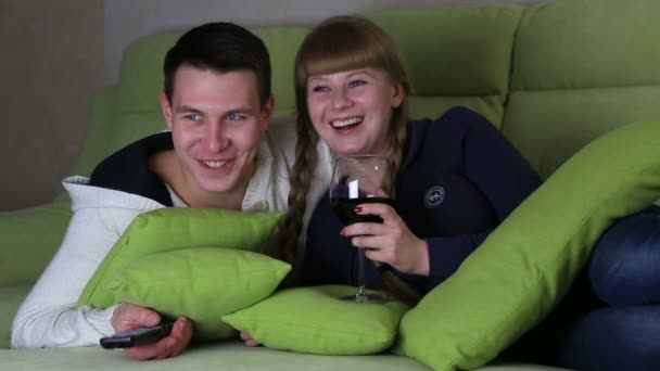 Νέοι ζευγάρι με ποτήρι κρασί βλέποντας κωμωδία στην τηλεόραση και γέλιο. — Αρχείο Βίντεο