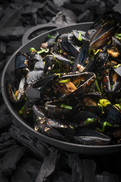 Steamed Mussels with vegetables in a black frying pan on the coa 스톡 사진