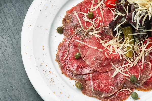 Carpaccio con aceitunas y parmesano en plato — Foto de Stock