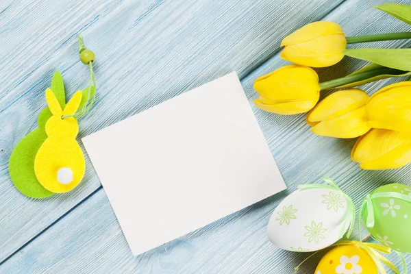 Ovos de Páscoa, tulipas e cartão em branco — Fotografia de Stock