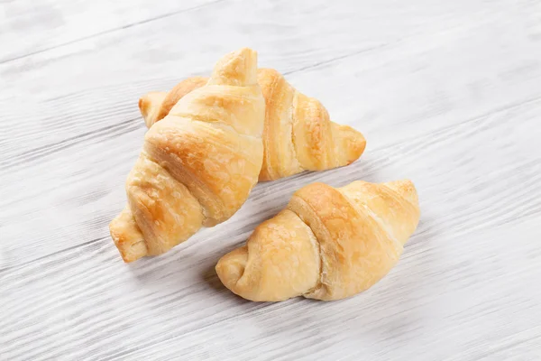 Čerstvé croissanty na dřevěném stole — Stock fotografie