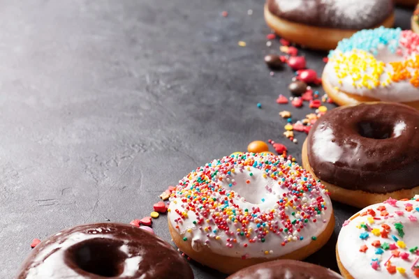 Donuts coloridos na mesa de pedra — Fotografia de Stock