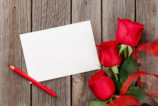 Rosas rojas y tarjeta de felicitación — Foto de Stock