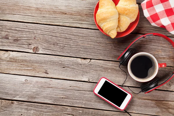 Verse croissants, koffie, smartphone en koptelefoon — Stockfoto