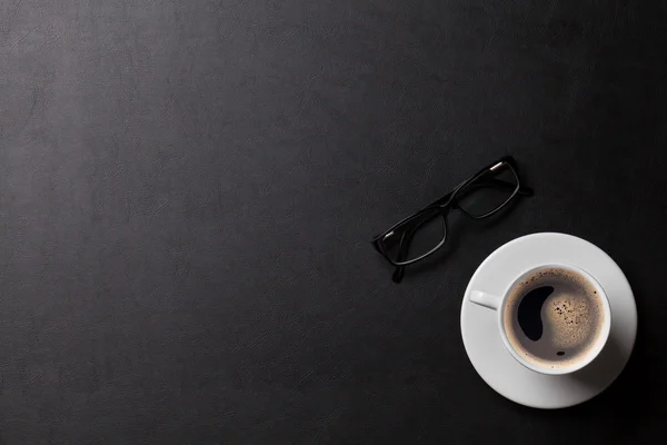 Skrivbord med kaffekoppen och glasögon — Stockfoto