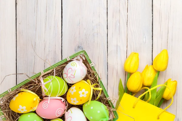 Bunte Eier und gelbe Tulpen — Stockfoto