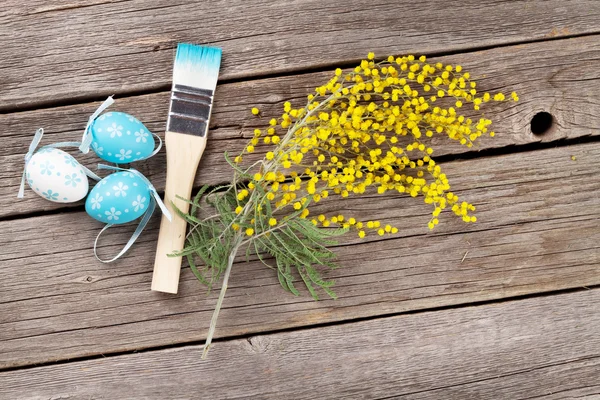 Ovos de páscoa coloridos, pincel e flor de mimosa — Fotografia de Stock