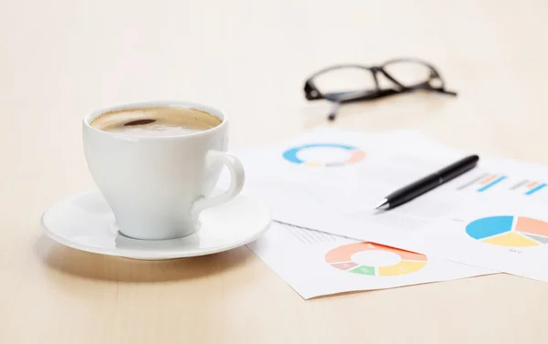 Office workplace with coffee cup and charts — Stock Photo, Image