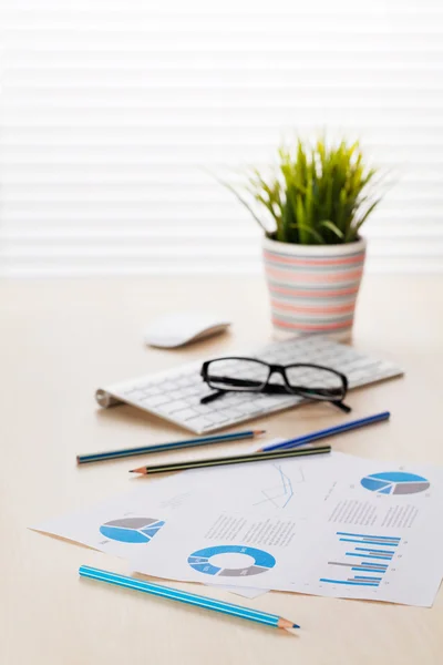 Escritório local de trabalho com pc, gráficos e planta — Fotografia de Stock