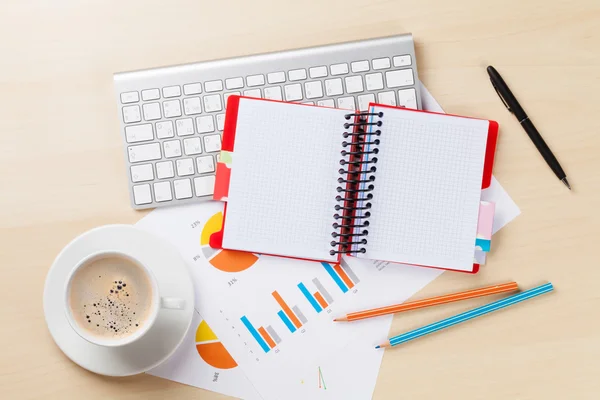 Office workplace with charts, coffee and notepad — Stock Photo, Image