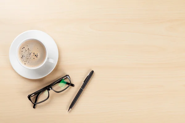 Skrivbord med kaffe, penna och glasögon — Stockfoto