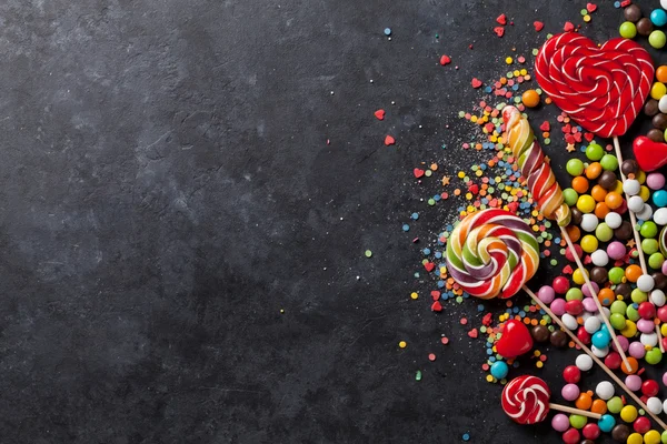 Coloridos caramelos y piruletas sobre piedra — Foto de Stock