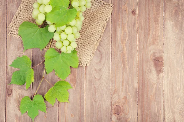 Ramo de uvas blancas con hojas sobre madera — Foto de Stock