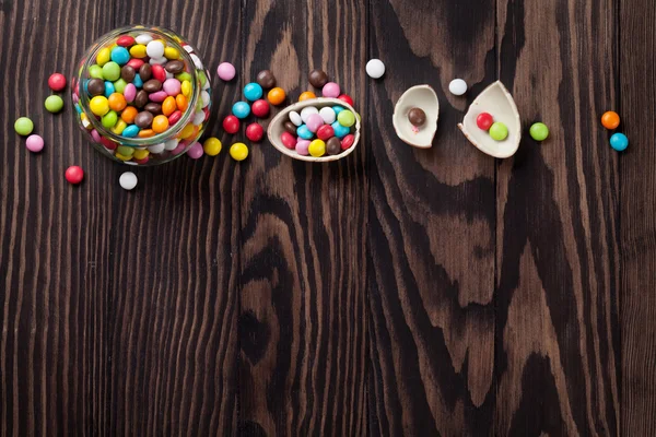 Barevné bonbóny na dřevěný stůl — Stock fotografie