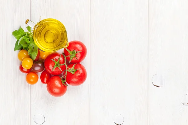 Olive oil, tomatoes, basil on wooden table — Stock Photo, Image