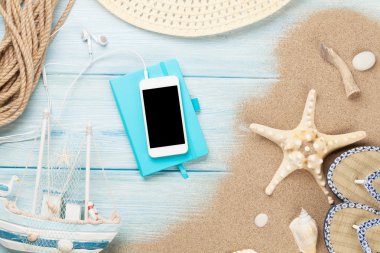 Smartphone ve deniz yıldızı ve kabukları ile ahşap üzerine not defteri