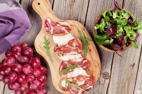 Prosciutto e mussarela na tábua de corte — Fotografia de Stock