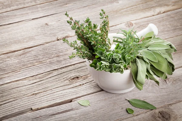 Herbes de jardin fraîches en mortier sur table en bois — Photo