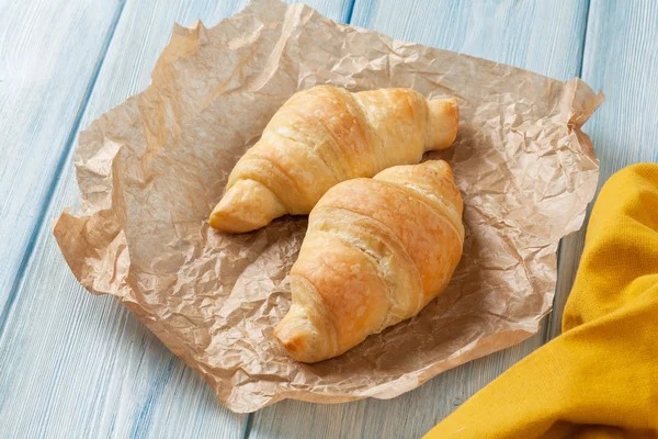 Čerstvé croissanty na dřevěném stole — Stock fotografie