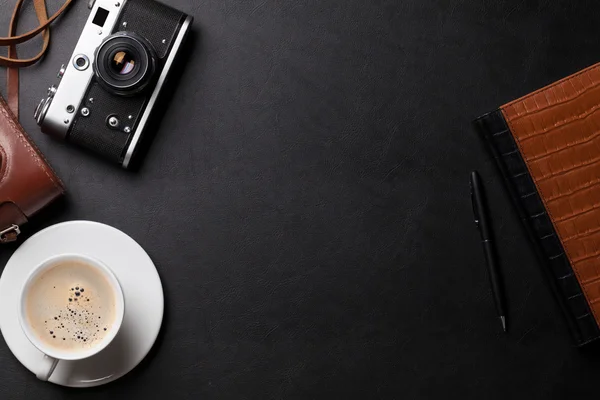 Skrivbord med kamera, kaffe och anteckningar — Stockfoto
