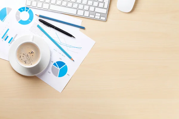 Office workplace with coffee cup and charts — Stock Photo, Image