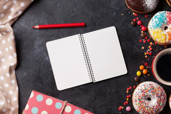 Bloco de notas, rosquinhas e café na mesa de pedra — Fotografia de Stock