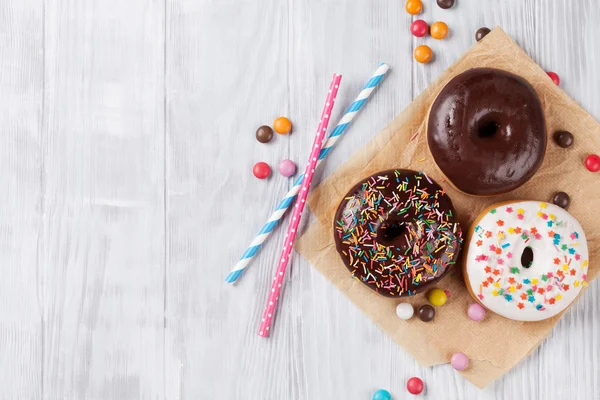 Donuts coloridos na mesa de madeira — Fotografia de Stock