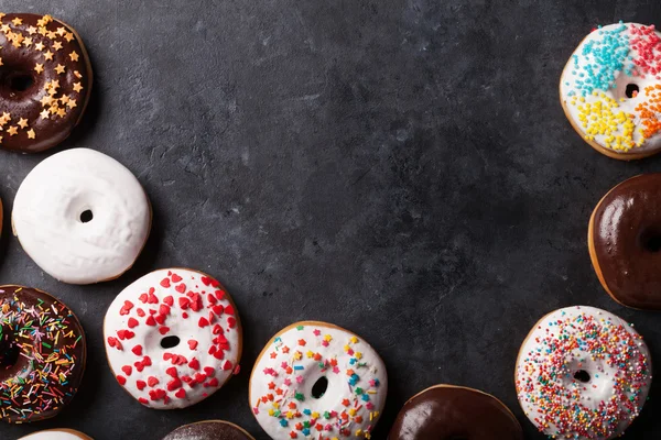 Donuts coloridos na mesa de pedra — Fotografia de Stock