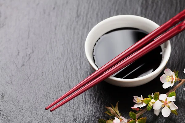 Palillos de sushi japoneses, tazón de salsa de soja y flor de sakura —  Fotos de Stock